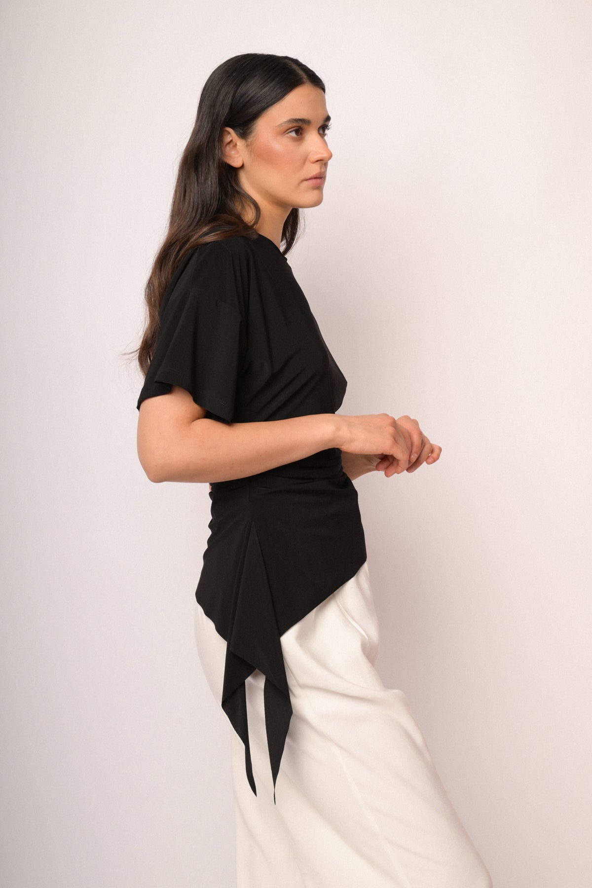 Maglia nera con arricciatura e fondo asimmetrico