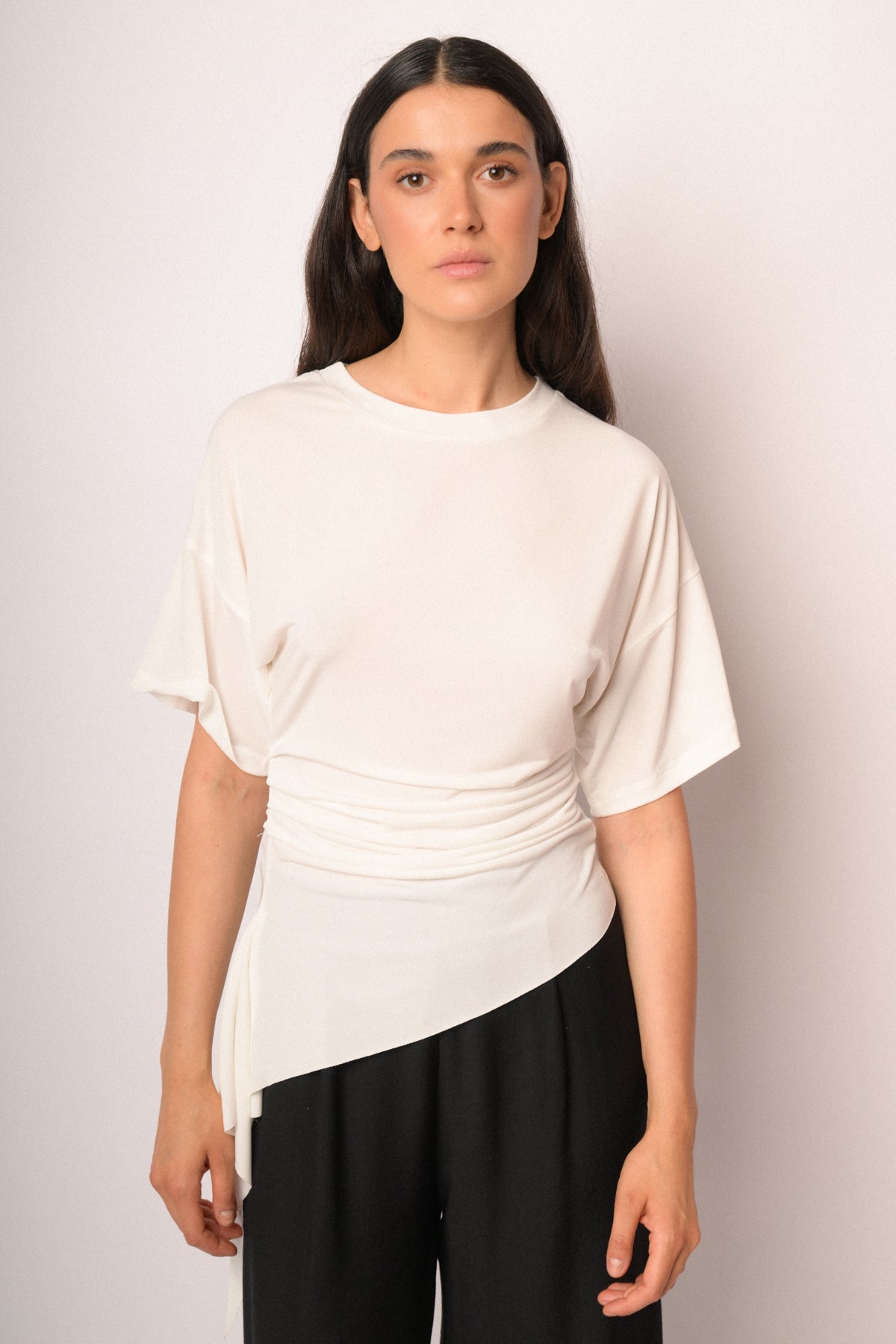 Maglia color panna drappeggiata con fondo asimmetrico
